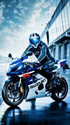 a man riding on the back of a blue and white motorcycle in front of a building