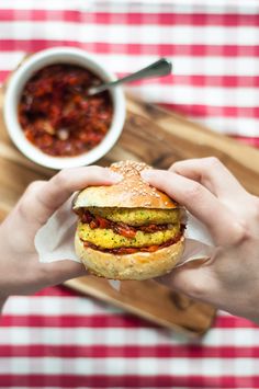 a person holding a sandwich in front of a bowl of chili