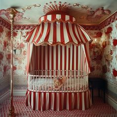 a red and white striped canopy bed in the corner of a room with wallpaper