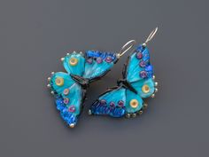 Handmade blue butterfly earrings featuring dichroic glass. Unique and lightweight, these drop earrings are crafted with care Crafted by skilled artisans, these unique earrings showcase the delicate beauty of butterflies. The iridescent blue dichroic glass wings shimmer in the light, capturing the essence of a fluttering butterfly. Lightweight and comfortable, they dangle gracefully, adding a touch of nature-inspired elegance to any outfit. Whether you're attending a garden party or simply want t Blue Butterfly Charm Dangle Earrings, Blue Dangle Earrings With Butterfly Charm, Handmade Blue Butterfly Earrings, Blue Butterfly Jewelry With Butterfly Print, Blue Butterfly Earrings For Gift, Blue Butterfly Earrings Gift, Blue Butterfly Earrings As Gift, Blue Butterfly Charm Earrings For Gift, Blue Butterfly Earrings