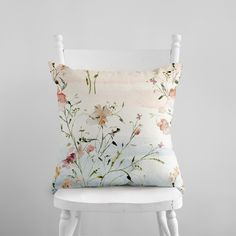 a white chair with a flowered pillow on it's back and side legs