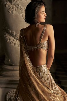 This lehenga set features all over mirror work and sequin embroidery in a linear pattern. The strappy blouse has crystal droplets at the waist. It is accompanied with a matching tissue organza dupatta.From Seema Gujral's Inara collection. DELIVERY TIMEPlease allow 8-12 weeks for your outfit to arrive. FABRIC DETAILSLehenga- Net, Blouse - Net, Dupatta - Tissue Organza Professional cleaning only. Seema Gujral Lehenga, Reception Lengha, Strappy Blouse, Seema Gujral, Mirror Work Lehenga, Net Blouse, Mirror Work Blouse, Work Lehenga, Gold Outfit