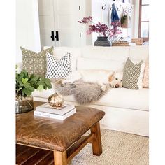 a living room filled with lots of furniture and flowers on top of a coffee table