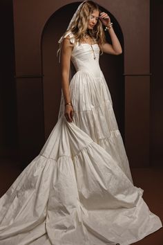 a woman in a white dress is posing for a photo with her hand on her head