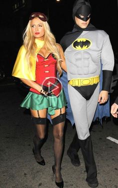 two people dressed up as batman and robin wayne walking down the street at night time