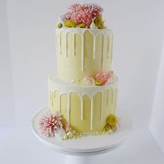 a three tiered cake with flowers on the top and bottom, sitting on a plate