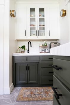 a kitchen with white cabinets and gray counter tops, gold pulls on the cupboards