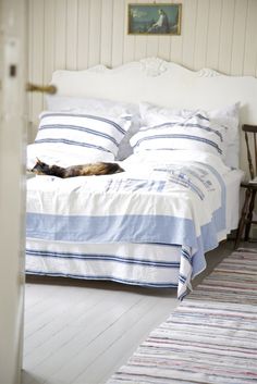 a cat laying on top of a bed next to a white headboard and foot board