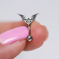 a close up of a person's finger holding a ring with a bat on it