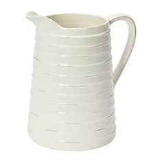 a white ceramic pitcher with wavy lines on it