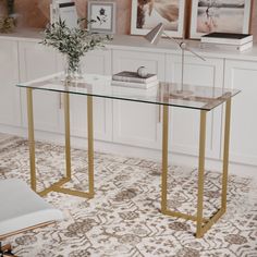 a glass table with gold legs in front of white cabinets and pictures on the wall