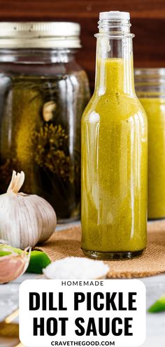 homemade dill pickle hot sauce in a glass bottle next to garlic and cloves