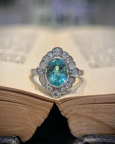 an open book with a ring sitting on top of it next to a blue stone