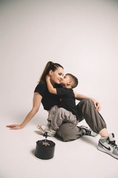 a man and woman sitting on the ground with their arms around each other