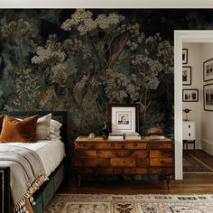 a bedroom with a bed, dresser and wallpaper on the walls in front of it