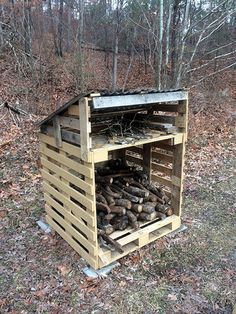 a pile of logs sitting inside of a wooden structure in the woods next to trees