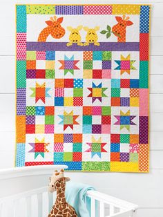 a baby crib with a colorful quilt hanging on the wall