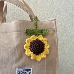 a crocheted sunflower sits on top of a canvas tote bag,