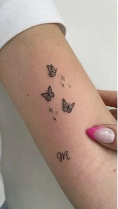 a woman's arm with butterflies and the letter m tattooed on her left side