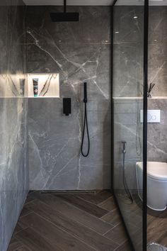 a bathroom with marble walls and flooring next to a shower head mounted on the wall