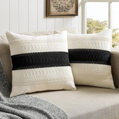 two black and white pillows sitting on top of a couch