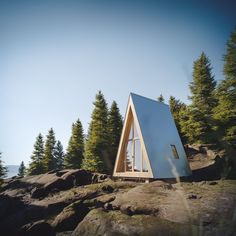 a triangular shaped building on top of a rocky hill with trees in the back ground