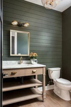 a white toilet sitting next to a sink in a bathroom under a chandelier