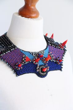 a white mannequin with a blue and red beaded necklace on it's neck