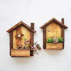 two wooden birdhouses with plants and pine cones on them