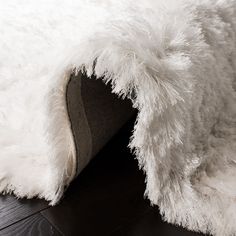 a close up of a white fluffy rug on a wooden floor