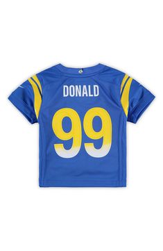 Your young fan will capture their team's identity in a fresh and innovative way when they wear this Los Angeles Rams Aaron Donald Game Jersey from Nike. It features Los Angeles Rams graphics to show who they support. Before they head to the next Los Angeles Rams game, make sure your youngster has this incredible jersey so that everyone knows who they're backing. Graphic Print Jersey For Fan Apparel, Short Sleeve Jersey With Graphic Print For Fans, Graphic Print Short Sleeve Jersey For Fan Gear, Nike Football Season Jersey With Team Name, Nike Jersey With Team Name For Football Season, Nike Tops With Letter Print For Team Events, Team-colored Graphic Print Jersey For Game Day, Sports Season Jersey With Graphic Print For Fans, Blue Fan Apparel Tops For Team Events