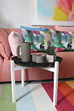 a living room with a pink couch and coffee table on top of the rug in front of it