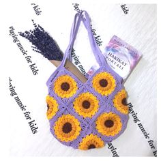 a crocheted bag with yellow and purple flowers on the front is sitting on a white surface