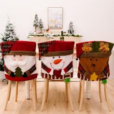 three snowmen sitting on wooden stools in front of a christmas tree and fireplace