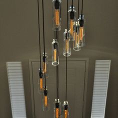 a chandelier made out of glass bottles hanging from it's ceiling in front of a door