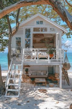 a white house on the beach with stairs leading up to it's second floor