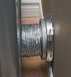 a close up of a metal object on the ground near a wall and door with wire wrapped around it