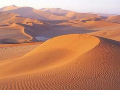 sand dunes in the desert with mountains in the background