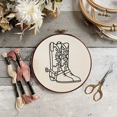 a pair of cowboy boots is on the table next to some yarn and scissors