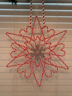 a candy cane snowflake hanging on the window sill in front of blinds