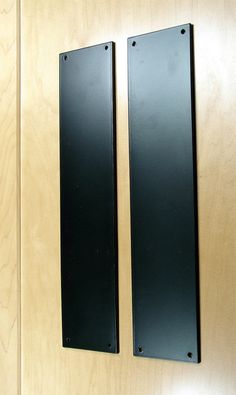 two black door handles on a wooden wall