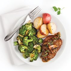 a white plate topped with meat, potatoes and broccoli next to a fork