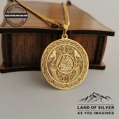 a gold necklace with an emblem on it and a wooden box in the background that says land of silver as you imagine