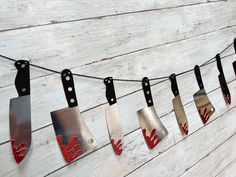 a line of kitchen utensils hanging from a string on a white wooden wall