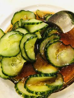 a white plate topped with sliced cucumbers and sauce