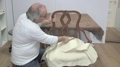 an older man is working on a chair that has been upholstered with fabric