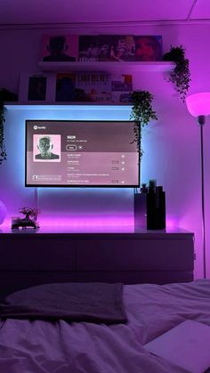 a bedroom with purple lighting and a flat screen tv mounted on the wall above it