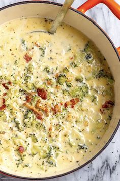 a pot filled with broccoli and cheese on top of a marble countertop