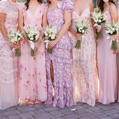 a group of women standing next to each other wearing dresses and holding bouquets in their hands