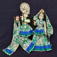 two figurines sitting on top of each other wearing green and blue dresses with matching headdress